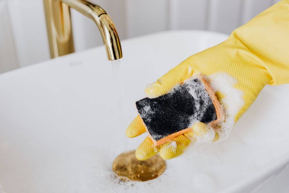 person washing dishes with sponge