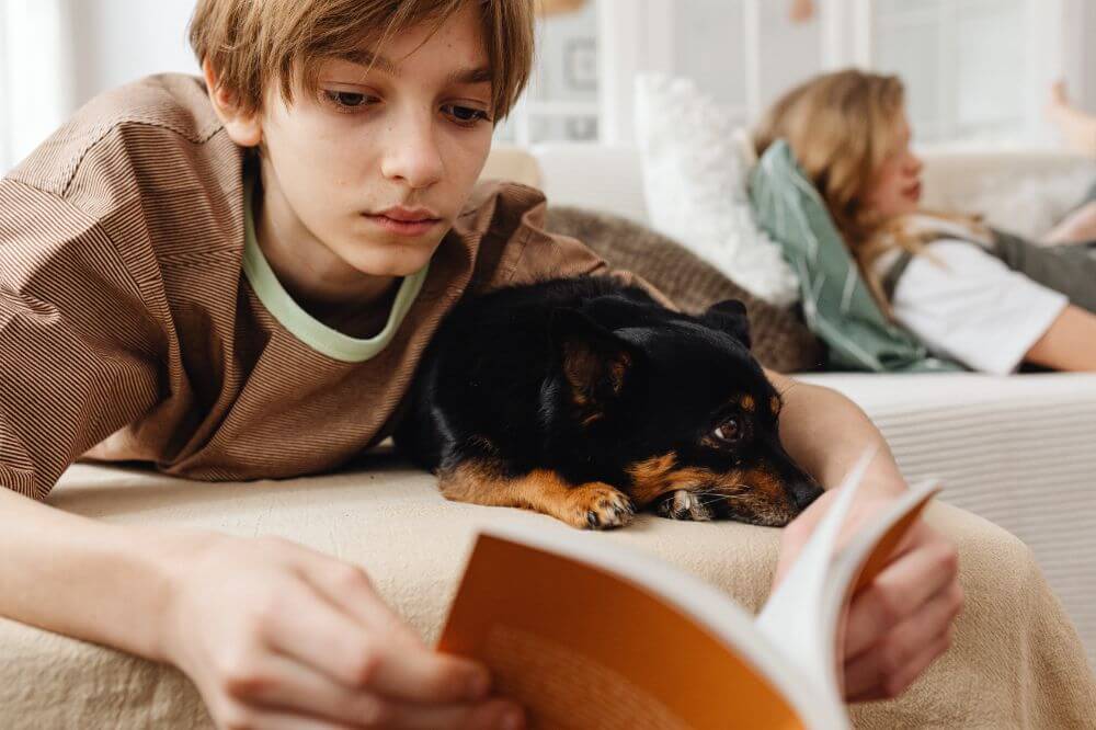 kid reading a book with a puppy